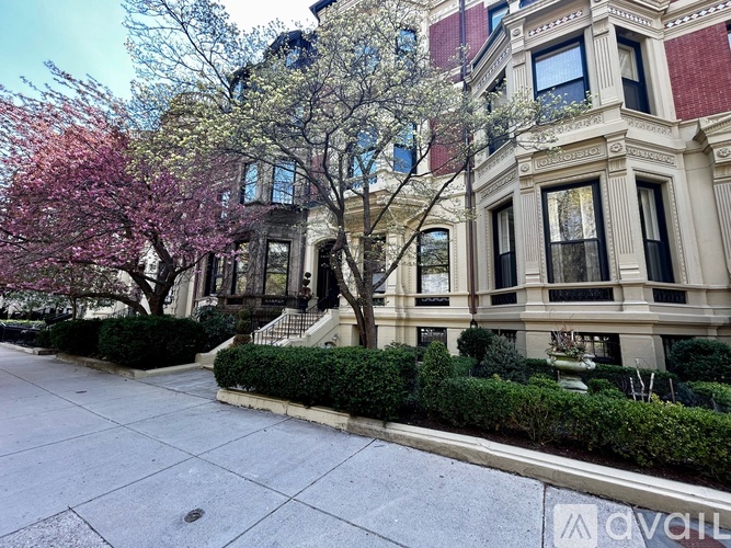 A tree with pink flowers is in front of a building.