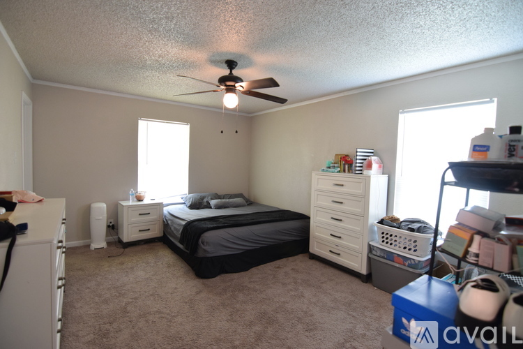 A bedroom with a bed, dresser, and a ceiling fan.