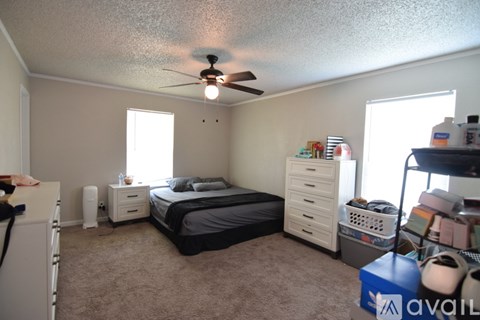 A bedroom with a bed, dresser, and a ceiling fan.