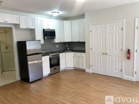 A kitchen with white cabinets and a black fridge.