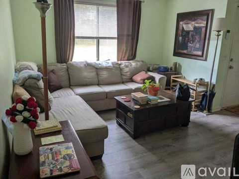 A living room with a white couch, a coffee table with a vase of flowers, and a painting on the wall.