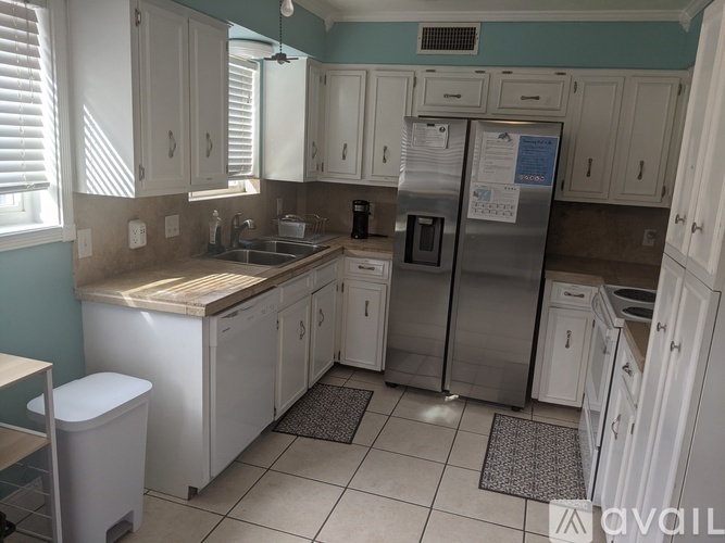 A kitchen with white cabinets and a stainless steel refrigerator.