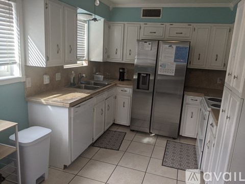 A kitchen with white cabinets and a stainless steel refrigerator.