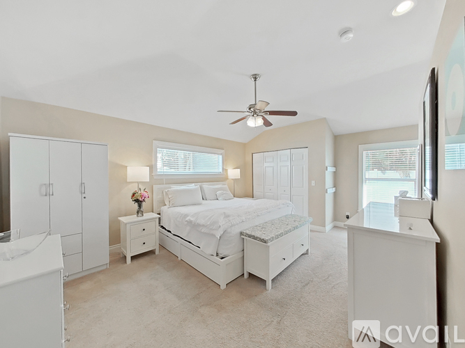 A bedroom with a large bed, a dresser, and a ceiling fan.