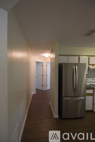 A kitchen with a stainless steel refrigerator and wooden floors.