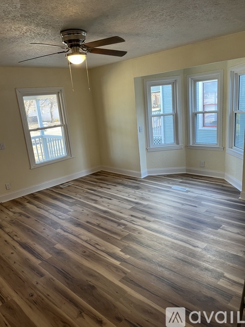 A room with wooden flooring and a ceiling fan.