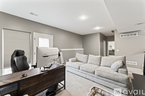 A modern living room with a grey couch and a wooden desk.