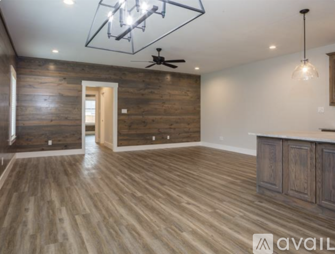 A spacious room with wooden flooring and a ceiling fan.