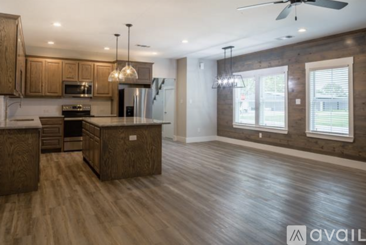 A spacious kitchen with wooden floors and a ceiling fan.