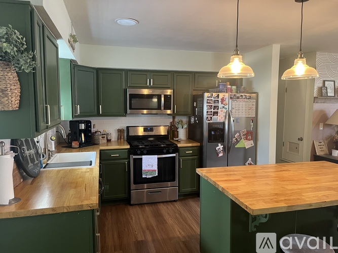 A kitchen with green cabinets and a wooden island.