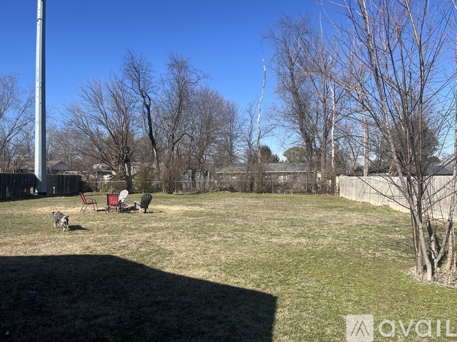 A backyard with a lawn, trees, and a fence.