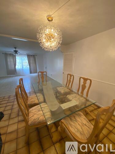 A dining room with a glass table and wooden chairs.
