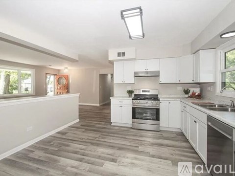 A modern kitchen with white cabinets and a wooden floor.