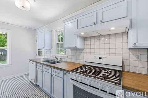 A kitchen with a white stove top oven and white cabinets.