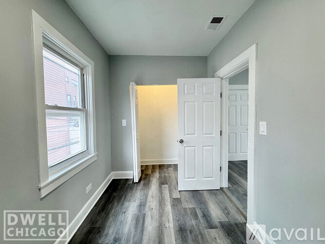 A room with a white door and a window with a view of a building outside.