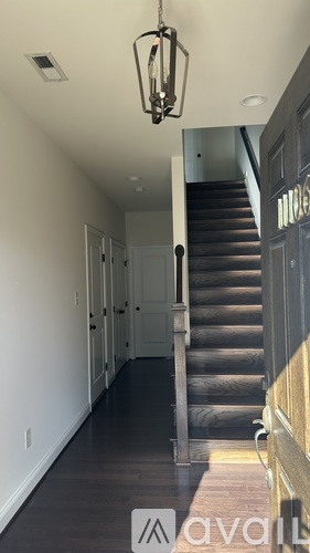A hallway with a staircase and a chandelier.
