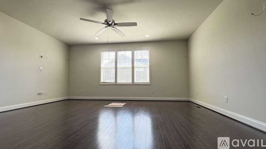 A spacious room with a ceiling fan and a window with blinds.