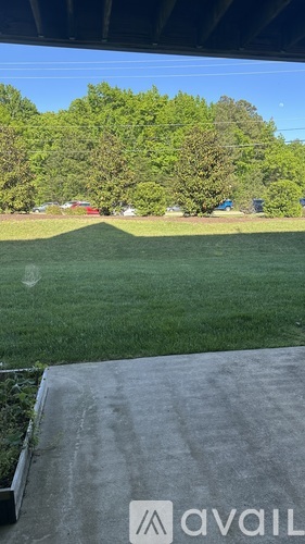 A grassy field with a few cars and trees in the background.