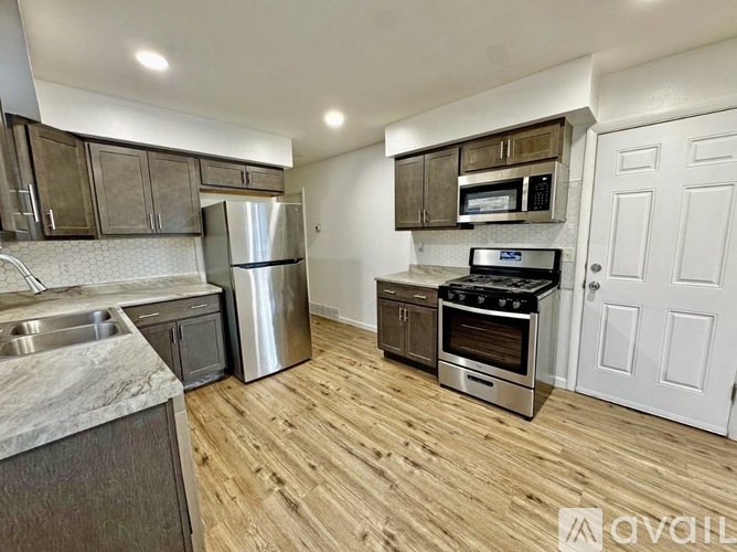 A kitchen with a stainless steel refrigerator, microwave, oven, and sink.