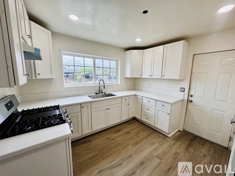 A kitchen with white cabinets and a black stove top.