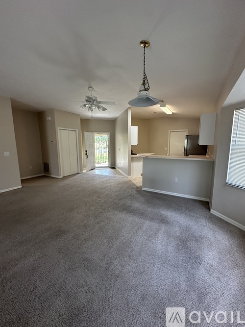 A spacious living room with a ceiling fan and carpeted floor.