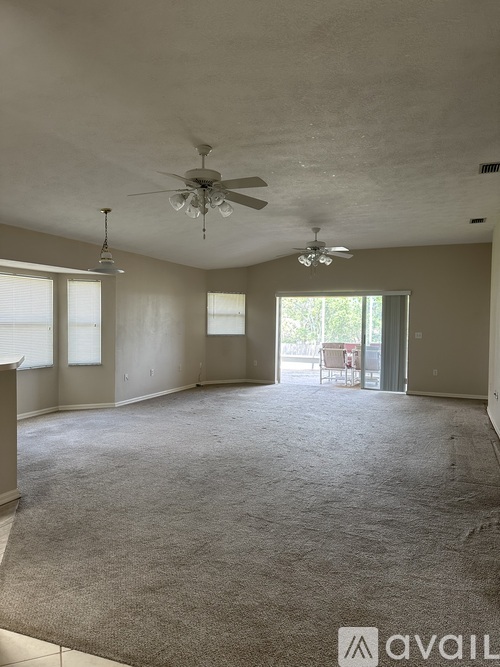 A spacious room with a ceiling fan and carpeted floor.