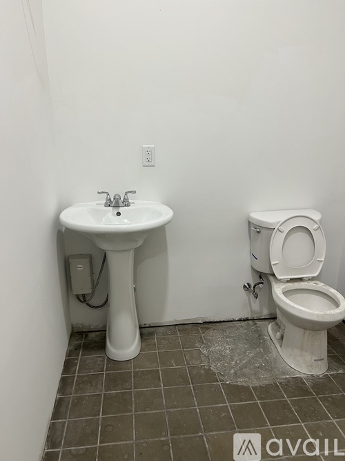 A white pedestal sink with a toilet next to it in a bathroom.