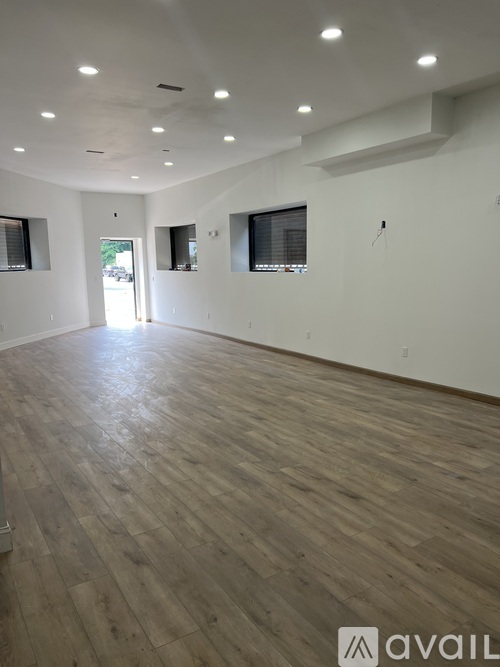 A spacious room with wooden flooring and white walls.
