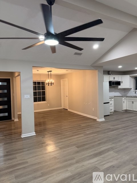A spacious kitchen and living room with a ceiling fan.