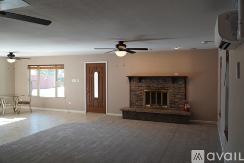 A living room with a fireplace and a ceiling fan.