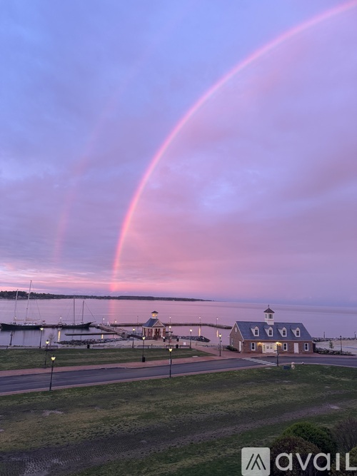 A rainbow arches over a building with a blue roof and white trim.
