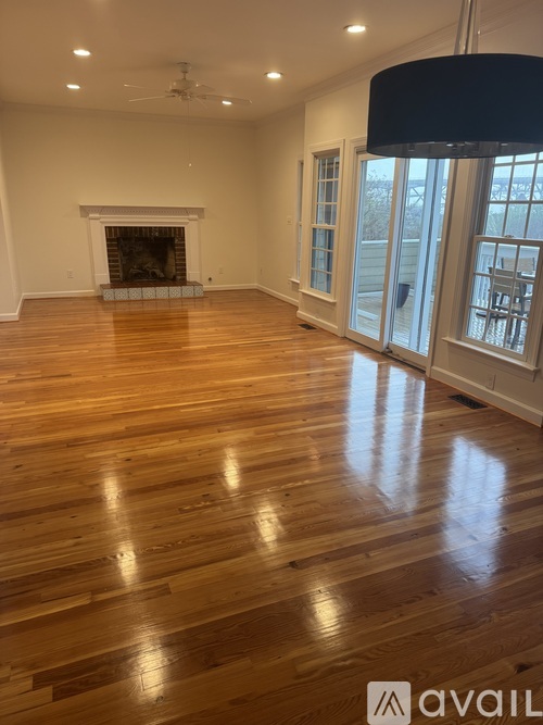 A spacious room with a fireplace and wood flooring.