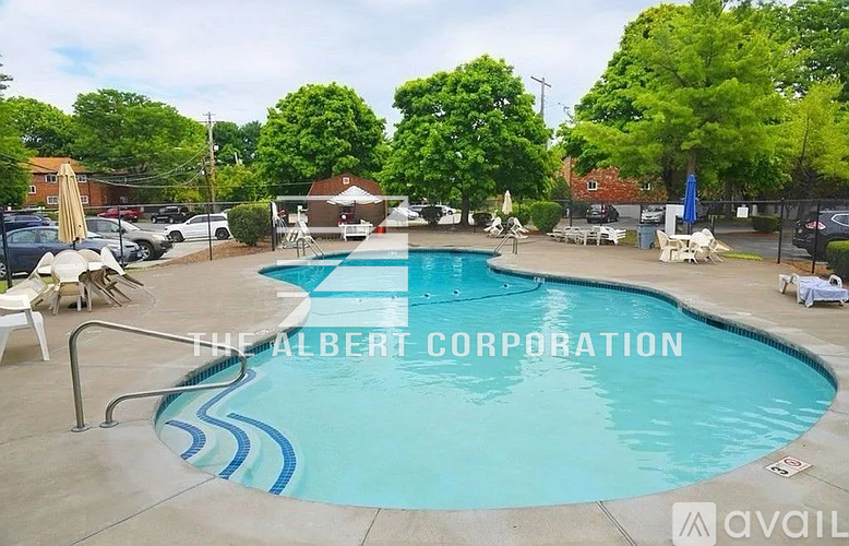A pool surrounded by trees and chairs with a sign that says "The Albert Corporation".