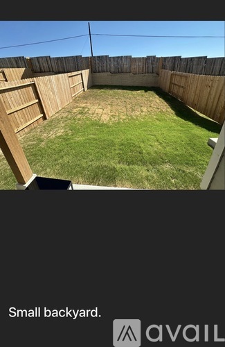 A small backyard with a wooden fence and a grassy area.