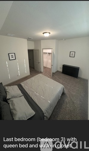 A bedroom with a queen bed and walk-in closet.