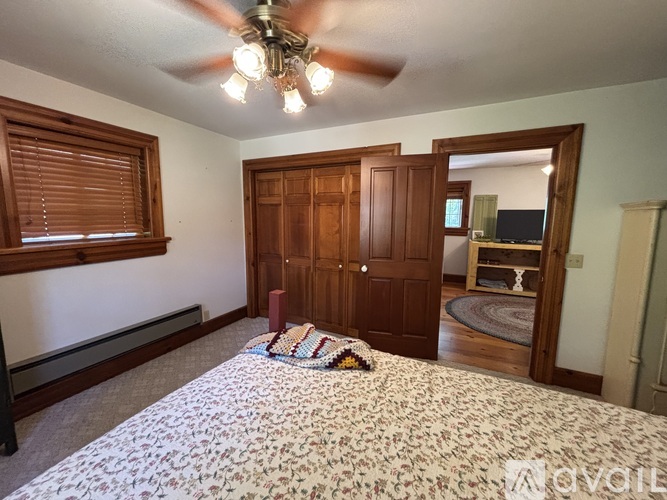 A bedroom with a bed, a ceiling fan, and a wooden door.