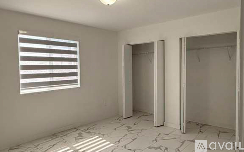 A room with a window and two open closets.