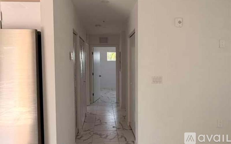 A long hallway with a marble floor and white walls.