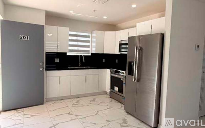 A kitchen with a black countertop and a refrigerator with a door numbered 201.