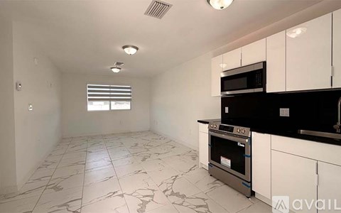 A kitchen with white cabinets and black countertops.