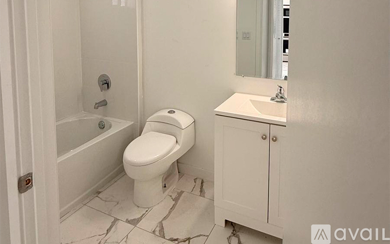 A white toilet in a bathroom with a white cabinet and a mirror.