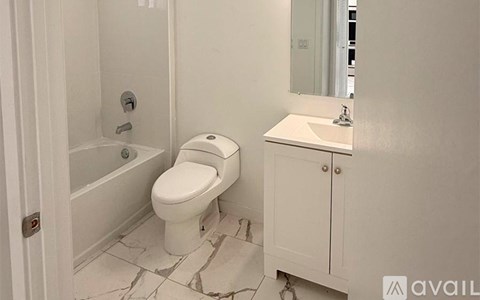 A white toilet in a bathroom with a white cabinet and a mirror.
