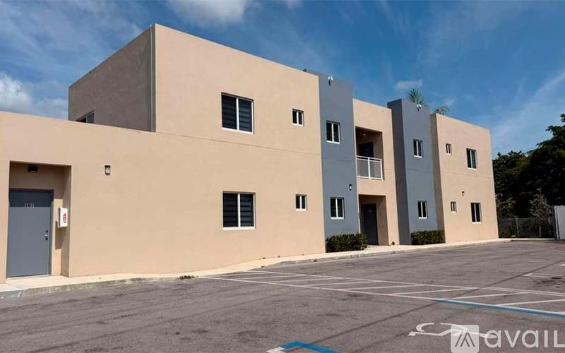 A modern building with a flat roof and a parking lot in front.