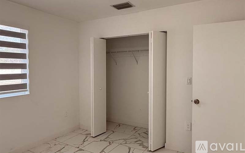 A room with a white door and a window with blinds.