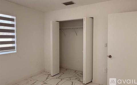 A room with a white door and a window with blinds.