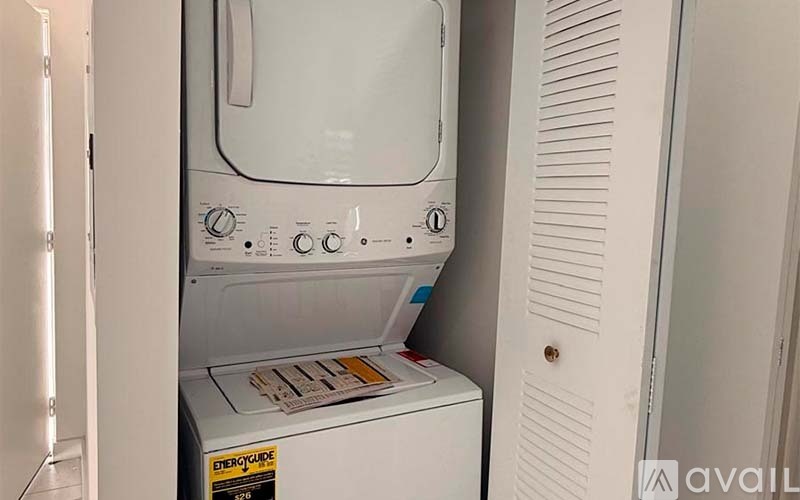 A white dryer is in a small space next to a white wall.