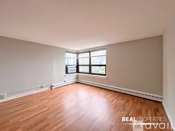 A room with wooden flooring and a window with blinds.