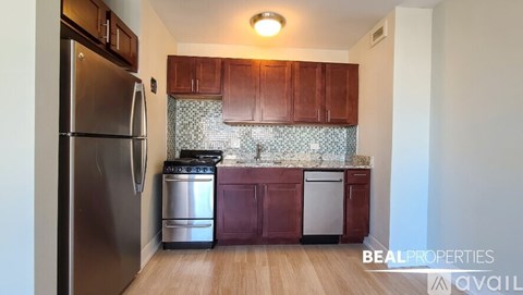 A kitchen with a stainless steel refrigerator and wooden cabinets.