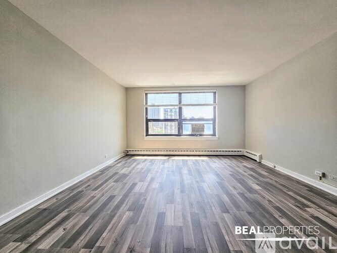 A room with wooden flooring and a window showing a city view.