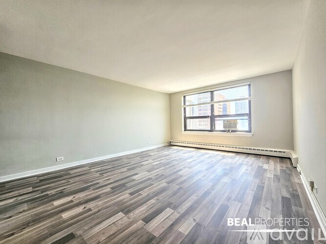 A room with wooden flooring and a window showing a city view.